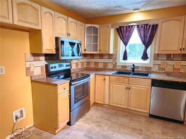 1519 Palmer Dr, Fayetteville, NC 28303 - kitchen featuring stainless steel appliances, light brown cabinetry, decorative backsplash, glass insert cabinets, and a textured ceiling