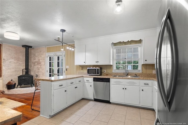 2613 N Edgewater Dr, Fayetteville, NC 28303 - kitchen with appliances with stainless steel finishes, a peninsula, white cabinetry, a wood stove, and a textured ceiling