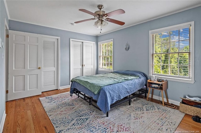 2613 N Edgewater Dr, Fayetteville, NC 28303 - bedroom featuring multiple closets, light wood-type flooring, crown molding, and ceiling fan