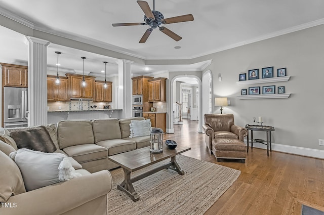 101 Tatum Ct, Holly Springs, NC 27540 - living room with arched walkways, a ceiling fan, wood finished floors, crown molding, and decorative columns