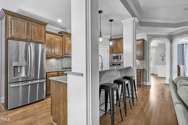 101 Tatum Ct, Holly Springs, NC 27540 - kitchen featuring appliances with stainless steel finishes, crown molding, arched walkways, light stone countertops, and light wood-type flooring