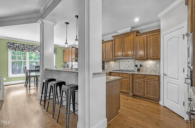 101 Tatum Ct, Holly Springs, NC 27540 - kitchen featuring ornamental molding, brown cabinets, a breakfast bar, light stone counters, and light wood finished floors