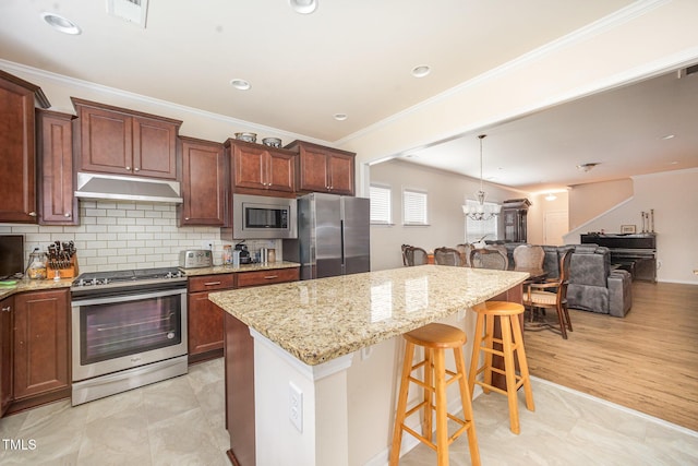 1204 E Rosedale Creek Dr, Durham, NC 27703 - kitchen with stainless steel appliances, under cabinet range hood, a breakfast bar, a chandelier, and crown molding