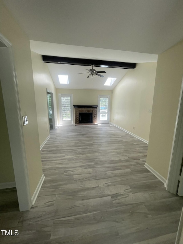 5 Sue Ann Ct, Durham, NC 27704 - unfurnished living room with a fireplace, a ceiling fan, a skylight, and wood finished floors