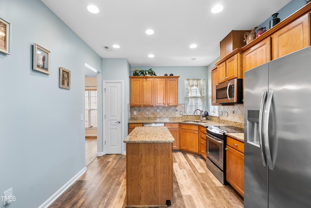 575 Tomkins Loop, Cary, NC 27519 - kitchen featuring stainless steel appliances, a kitchen island, light wood finished floors, tasteful backsplash, and light stone counters