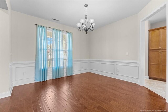 4817 Kiara Dr, Hope Mills, NC 28348 - empty room with a chandelier, wood finished floors, wainscoting, and a decorative wall