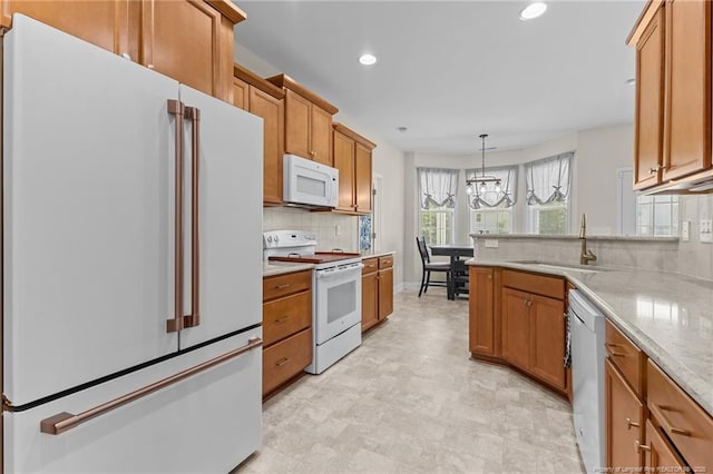 4817 Kiara Dr, Hope Mills, NC 28348 - kitchen with white appliances, backsplash, a chandelier, brown cabinetry, and recessed lighting