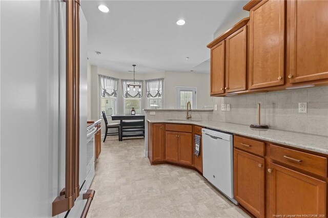 4817 Kiara Dr, Hope Mills, NC 28348 - kitchen featuring dishwasher, brown cabinetry, tasteful backsplash, a peninsula, and a chandelier