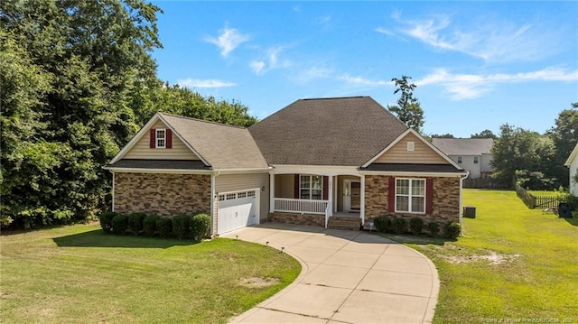 4817 Kiara Dr, Hope Mills, NC 28348 - view of front of home featuring stone siding, concrete driveway, a garage, a front lawn, and a porch