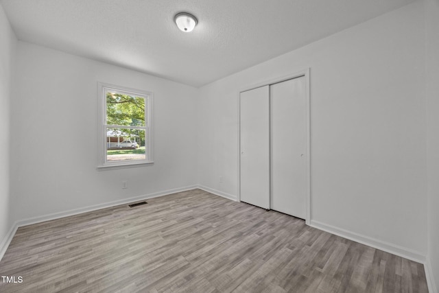 37 Weeping Willow Ln, Lillington, NC 27546 - unfurnished bedroom with wood finished floors, a closet, and a textured ceiling