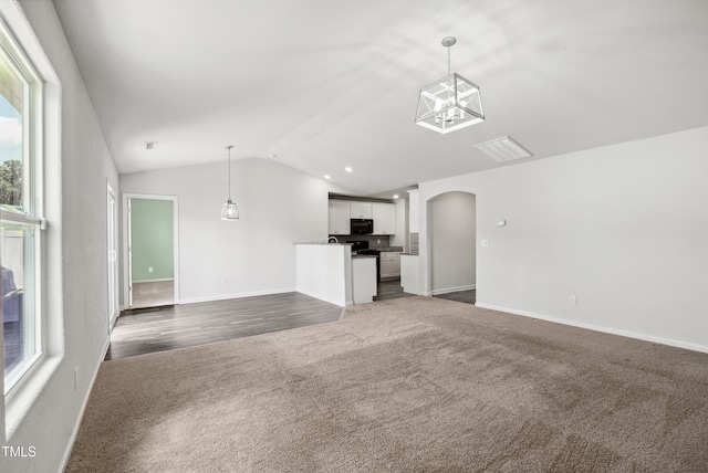 1561 Dorsett Ln, Creedmoor, NC 27522 - unfurnished living room featuring dark carpet, vaulted ceiling, arched walkways, healthy amount of natural light, and a chandelier