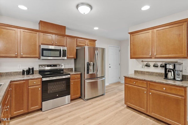 161 Jacob St, Holly Springs, NC 27540 - kitchen featuring appliances with stainless steel finishes, light wood-style flooring, brown cabinets, and recessed lighting