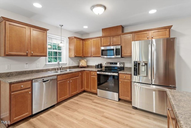 161 Jacob St, Holly Springs, NC 27540 - kitchen featuring appliances with stainless steel finishes, brown cabinetry, hanging light fixtures, light wood-type flooring, and recessed lighting