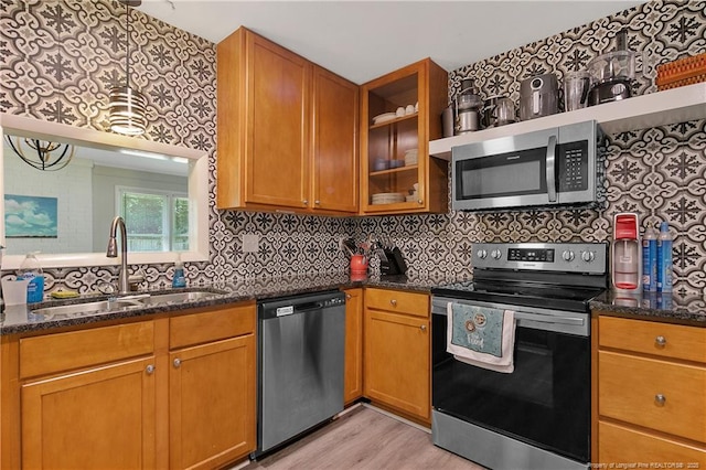 6501 Senator Dr, Fayetteville, NC 28304 - kitchen featuring appliances with stainless steel finishes, dark stone countertops, light wood-style flooring, glass insert cabinets, and tasteful backsplash