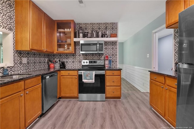 6501 Senator Dr, Fayetteville, NC 28304 - kitchen with appliances with stainless steel finishes, light wood-type flooring, wainscoting, dark stone counters, and glass insert cabinets