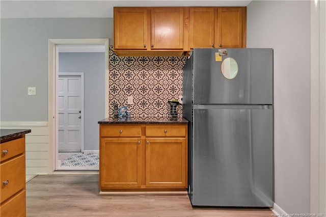 6501 Senator Dr, Fayetteville, NC 28304 - kitchen featuring freestanding refrigerator, decorative backsplash, light wood-type flooring, and dark stone countertops