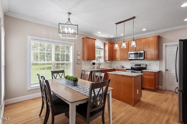1505 Mclaurin Ln, Fuquay Varina, NC 27526 - kitchen with appliances with stainless steel finishes, a center island, tasteful backsplash, light wood-style flooring, and ornamental molding
