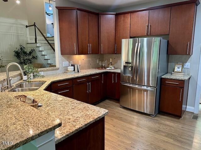 1113 Bexley Hills Bnd, Apex, NC 27502 - kitchen featuring stainless steel fridge with ice dispenser, tasteful backsplash, light stone counters, and light wood-type flooring