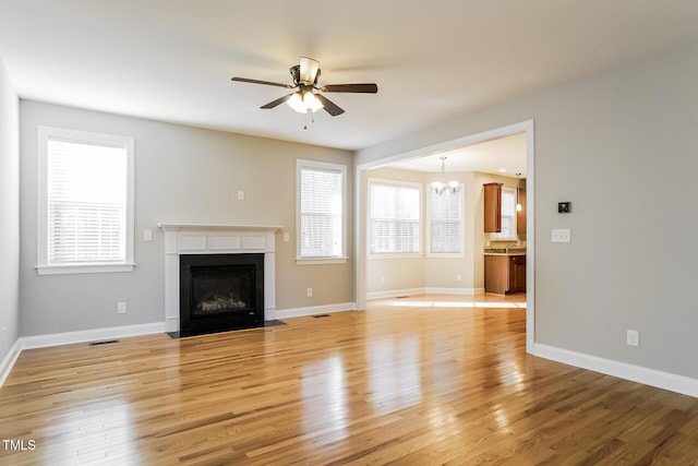 165 Sutherland Dr, Franklinton, NC 27525 - unfurnished living room featuring a chandelier, ceiling fan, a fireplace with flush hearth, and light wood finished floors