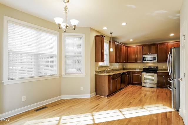 165 Sutherland Dr, Franklinton, NC 27525 - kitchen with stainless steel appliances, light stone counters, light wood-style floors, a chandelier, and hanging light fixtures