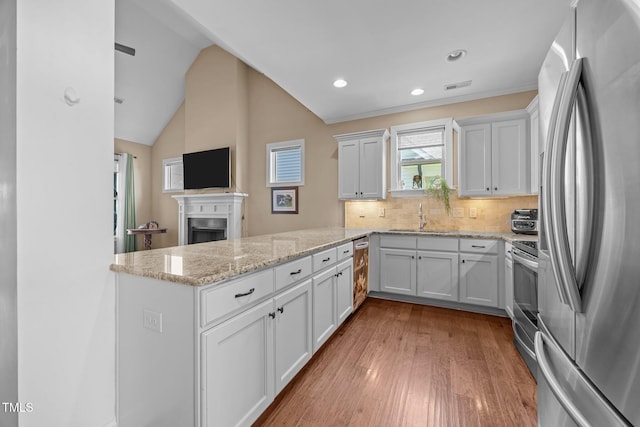 80 Scarlet Bell Dr, Youngsville, NC 27596 - kitchen featuring appliances with stainless steel finishes, a peninsula, a fireplace, wood finished floors, and white cabinets