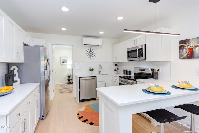 1309 Hudson Ave Unit D6, Durham, NC 27705 - kitchen with stainless steel appliances, an AC wall unit, a peninsula, light wood-style floors, and white cabinets