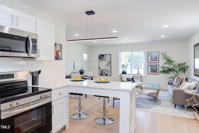 1309 Hudson Ave Unit D6, Durham, NC 27705 - kitchen with appliances with stainless steel finishes, a peninsula, open floor plan, light wood-style floors, and white cabinets