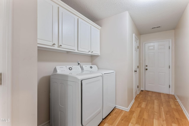 3109 Gold Dust Ln, Willow Springs, NC 27592 - laundry area featuring washing machine and clothes dryer, cabinet space, light wood finished floors, and a textured ceiling