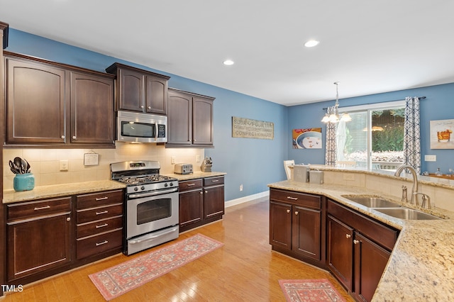 1413 Lily Creek Dr, Cary, NC 27518 - kitchen with appliances with stainless steel finishes, light wood-style floors, dark brown cabinets, decorative backsplash, and light stone countertops
