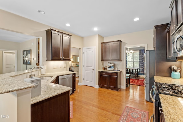 1413 Lily Creek Dr, Cary, NC 27518 - kitchen featuring appliances with stainless steel finishes, dark brown cabinetry, light wood-style floors, light stone counters, and backsplash