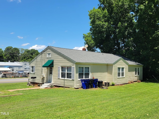 411 W Raleigh St, Siler City, NC 27344 - rear view of house with a yard, a shingled roof, and a chimney