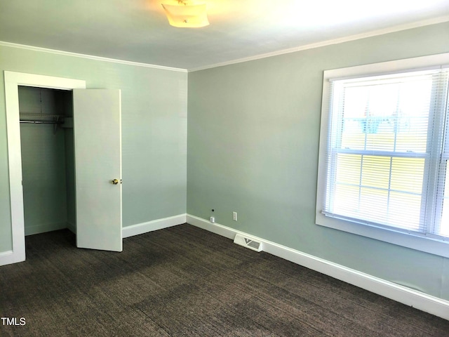 411 W Raleigh St, Siler City, NC 27344 - unfurnished bedroom with dark carpet, crown molding, and a closet