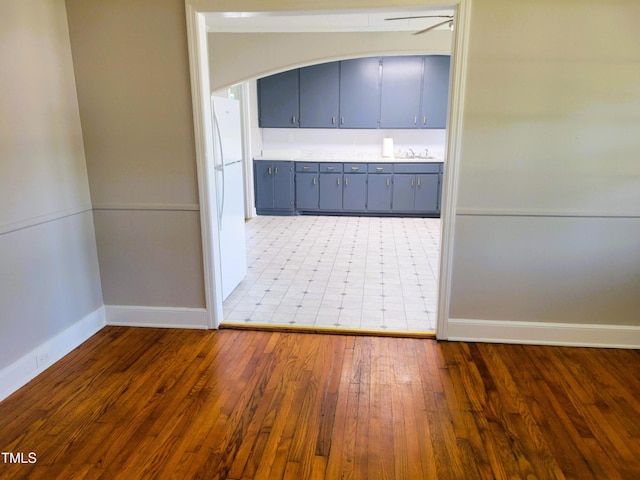 411 W Raleigh St, Siler City, NC 27344 - kitchen with gray cabinetry, freestanding refrigerator, wood finished floors, light countertops, and arched walkways