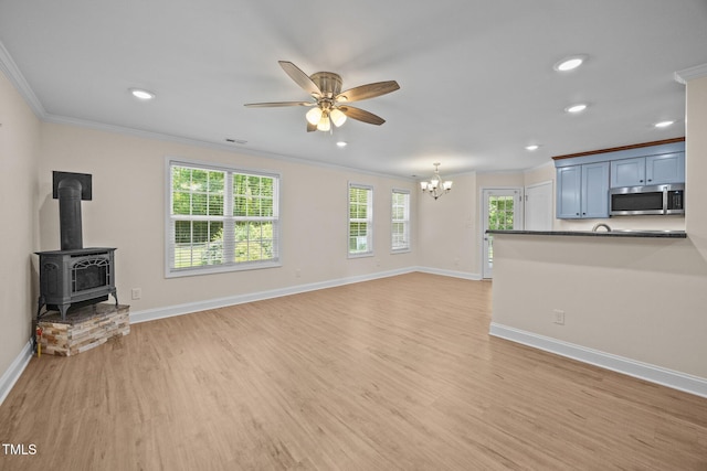 200 Cornerstone Dr, Franklinton, NC 27525 - unfurnished living room featuring crown molding, a chandelier, ceiling fan, light wood-type flooring, and a wood stove