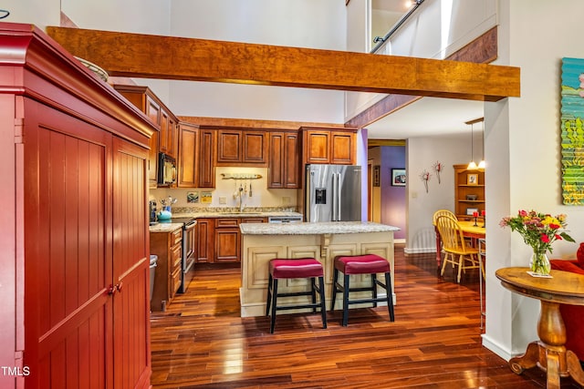 206 Lisa Dr, Carrboro, NC 27510 - kitchen featuring appliances with stainless steel finishes, dark wood finished floors, a kitchen island, a breakfast bar area, and light stone countertops