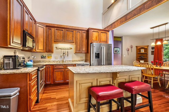 206 Lisa Dr, Carrboro, NC 27510 - kitchen featuring appliances with stainless steel finishes, light wood finished floors, a center island, a breakfast bar area, and pendant lighting