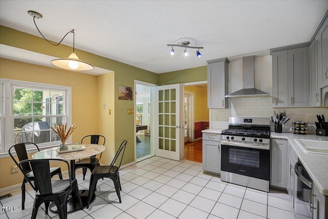 619 Ashe Ave, Cary, NC 27511 - kitchen featuring stainless steel range with gas stovetop, wall chimney range hood, gray cabinetry, and a textured ceiling