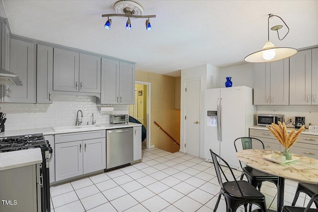 619 Ashe Ave, Cary, NC 27511 - kitchen featuring stainless steel appliances, gray cabinetry, light countertops, backsplash, and a textured ceiling