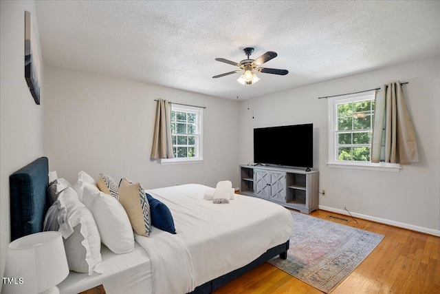 619 Ashe Ave, Cary, NC 27511 - bedroom featuring multiple windows, wood finished floors, a textured ceiling, and a ceiling fan