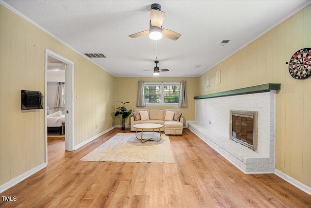 619 Ashe Ave, Cary, NC 27511 - unfurnished living room with ornamental molding, light wood-style floors, a fireplace, ceiling fan, and wood walls