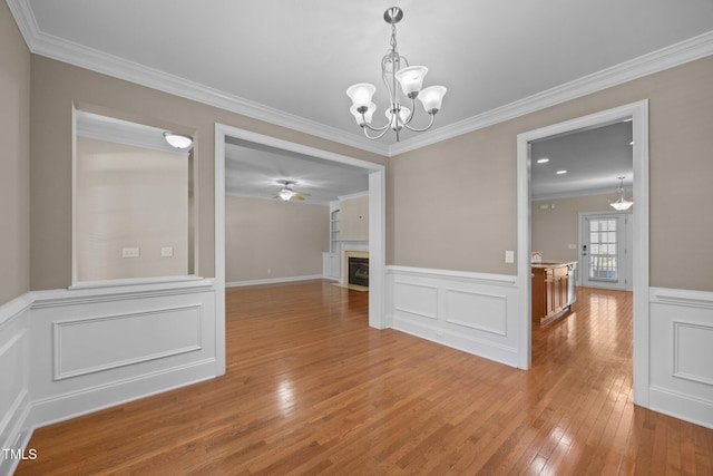 1012 Palace Garden Way, Raleigh, NC 27603 - unfurnished dining area with light wood finished floors, ornamental molding, a chandelier, a ceiling fan, and a fireplace with flush hearth