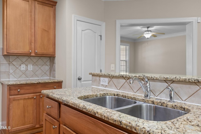 1012 Palace Garden Way, Raleigh, NC 27603 - kitchen featuring light stone counters, tasteful backsplash, ornamental molding, a ceiling fan, and brown cabinetry