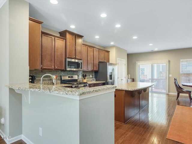 215 Brier Summit Pl, Durham, NC 27703 - kitchen featuring appliances with stainless steel finishes, a breakfast bar area, hardwood / wood-style floors, tasteful backsplash, and recessed lighting