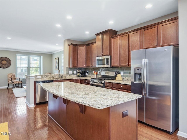 215 Brier Summit Pl, Durham, NC 27703 - kitchen featuring stainless steel appliances, a center island, wood finished floors, decorative backsplash, and ornamental molding