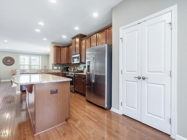 215 Brier Summit Pl, Durham, NC 27703 - kitchen with stainless steel appliances, light wood-style flooring, a breakfast bar, a peninsula, and decorative backsplash