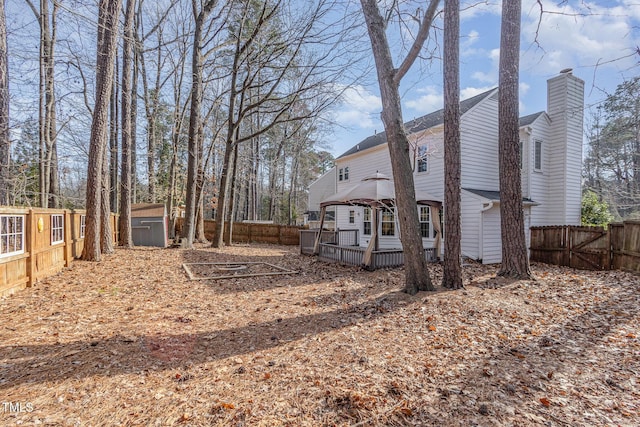 112 Solstice Cir, Cary, NC 27513 - view of side of home with a gazebo, a fenced backyard, a chimney, a wooden deck, and a storage unit