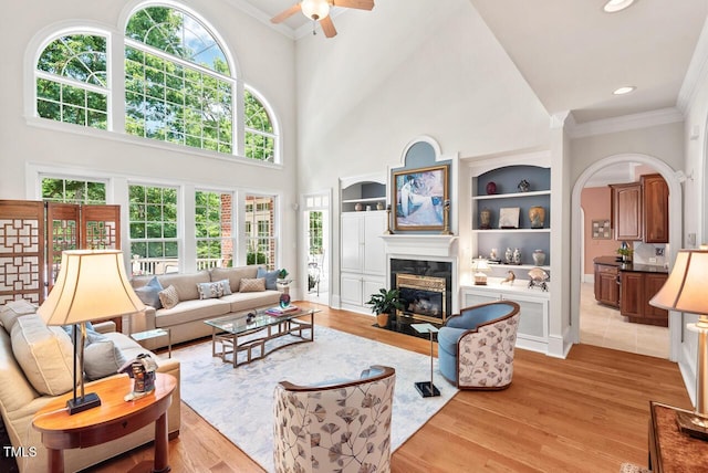 3606 Dairy Pond Pl, Durham, NC 27705 - living area featuring crown molding, a fireplace, a ceiling fan, light wood-style floors, and a towering ceiling