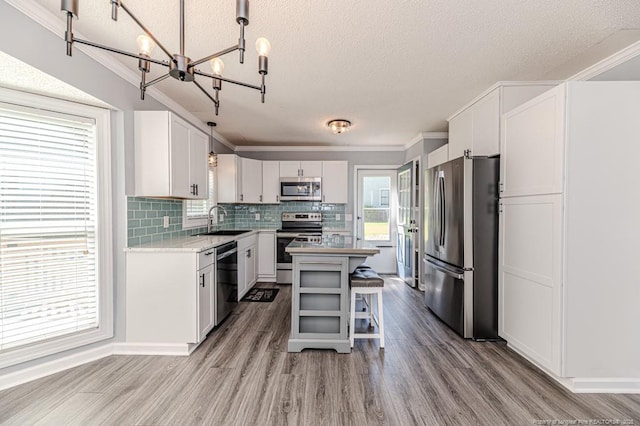 4101 Carson Dr, Sanford, NC 27332 - kitchen featuring stainless steel appliances, a chandelier, a textured ceiling, white cabinets, and decorative backsplash