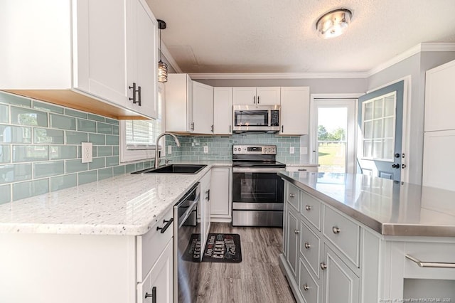 4101 Carson Dr, Sanford, NC 27332 - kitchen with stainless steel appliances, wood finished floors, light stone counters, white cabinetry, and ornamental molding