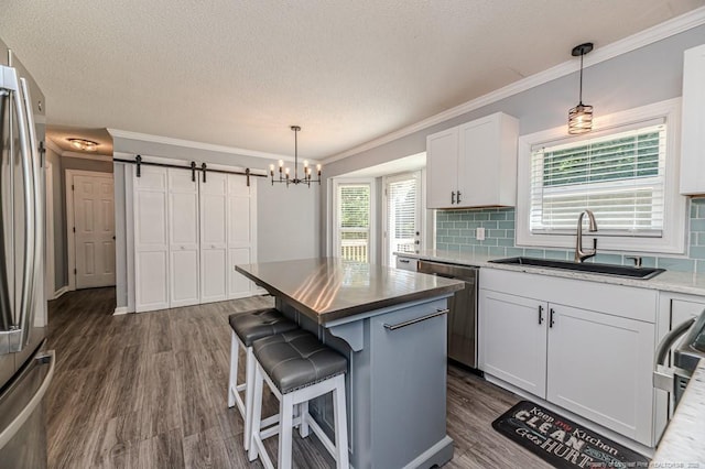 4101 Carson Dr, Sanford, NC 27332 - kitchen with appliances with stainless steel finishes, crown molding, a barn door, dark wood-type flooring, and decorative backsplash